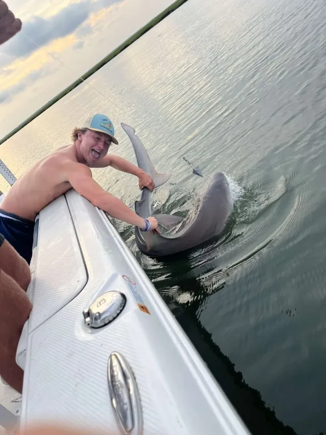 Angler posing beside a shark at the boat rail
